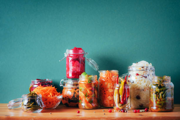 Assortment of various fermented and marinated food over wooden background, copy space. Fermented vegetables, sauerkraut, pepper, garlic, beetroot, korean carrot, cucumber kimchi in glass jars , gut health